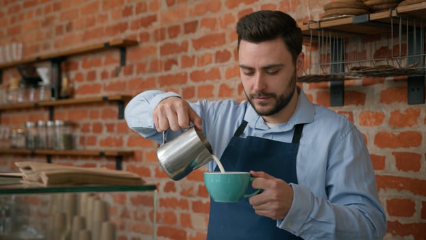 Caucasian man waiter barman barista in apron making coffee at counter in cafe male professional bartender cafeteria worker preparing tasty cappuccino make customer order looking at camera smiling photo