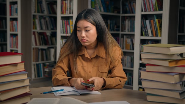 Sad frustrated stressed asian woman girl in university library checking email reading bad news on mobile phone disappointed chinese female student getting notification failing exam losing scholarship photo