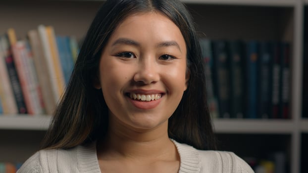 Close-up smiling asian korean woman turning to camera indoors happy chinese japanese ethnic girl student business lady businesswoman office employee posing near bookshelf headshot female portrait photo