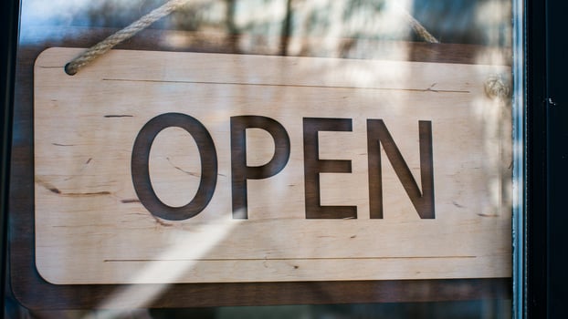 Close-up man waiter salesman turning signboard from closed to open on glass door male restaurant owner seller manager opens cafe shop businessman entrepreneur opening new store small business concept photo
