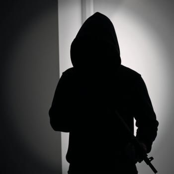 Silhouette of a hooded figure with a gun exuding mystery and danger photo