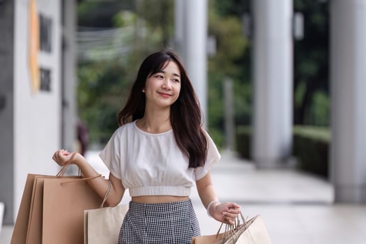 Young Woman Shopping with Paper Bags at a Modern Department Store on a Sunny Day photo
