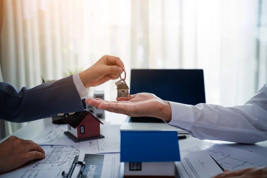 A man is handing a key to another man. The man holding the key is wearing a suit and tie. The other man is wearing a white shirt. Concept of professionalism and trust between the two men photo