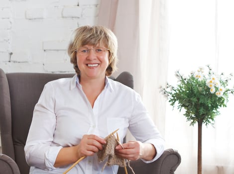 Portrait of a smiling middle age woman knitting on spokes photo