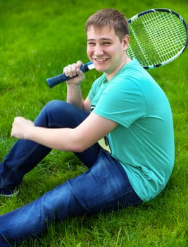 Teenage boy smiling while holding a tennis racket photo