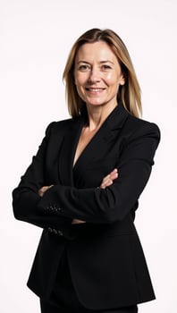 A professional businesswoman stands confidently against an isolating white backdrop dressed in a black suit with crossed arms photo