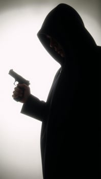 Hooded figure with gun in dark silhouette photo