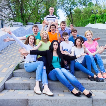 Group of smiling teenagers sitting on the stairs photo