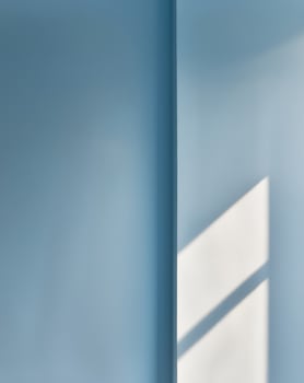 A blue wall with a window and a light shining on it photo