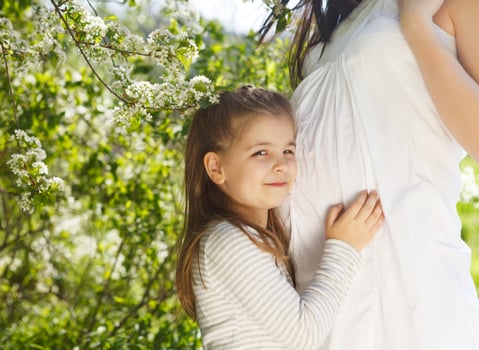 Happy pregnant mother and her little daughter photo