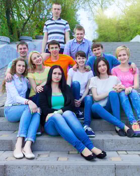 Group of smiling teenagers sitting outdoors photo