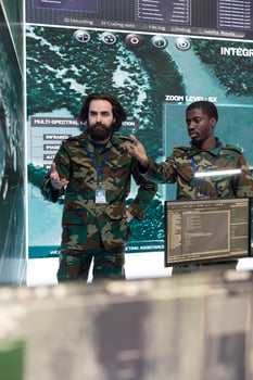 Professional army engineers gather intelligence for terrain operations, using surveillance CCTV footage in military power base. Soldiers examining important real time data on a big screen. photo
