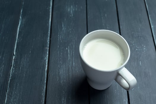 Glass of milk on table on blurred natural background photo