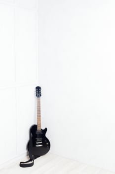 guitar propped in front of a white wall photo
