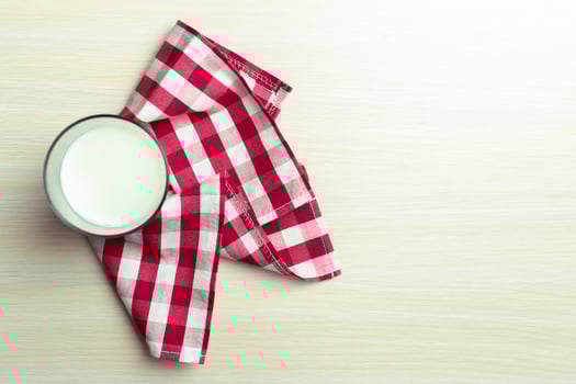Glass of milk on table on blurred natural background photo