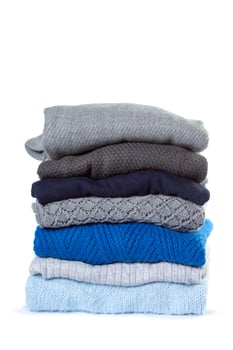 Stack of various sweaters isolated on white background photo