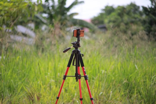 Tripod with Mounted Camera Standing in a Field of Lush Green Grass photo