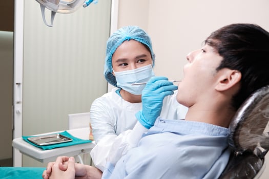 Asian female dentist examine young male patient teeth and toothache stomatology in dental clinic, well-being hygiene checks, and professional orthodontic healthcare work in doctor's office hospital. photo