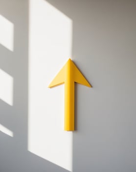 Yellow arrow pointing to the future on a white wall photo