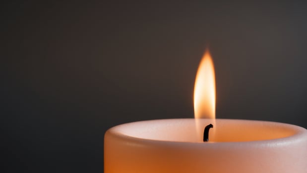 A single candle is lit in the dark photo