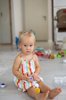 A beautiful blonde baby girl playing with a plastic montessori eggs photo