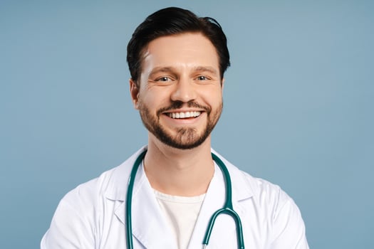 Portrait of smiling, friendly doctor posing wearing white coat isolated on blue background photo