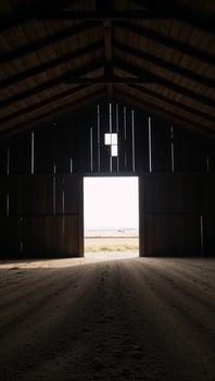 Large empty barn featuring an illuminated entranceway photo