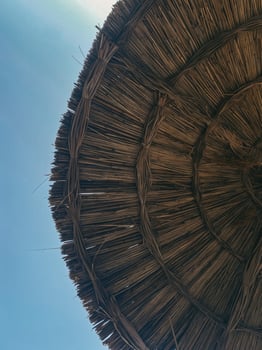 Straw parasol on clear blue sky background. Woven texture of natural fibers, evoking summer relaxation and beach vibes. Perfect for vacation and leisure designs photo