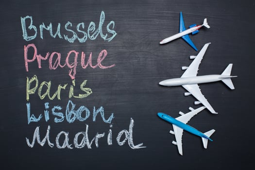 Traveling concept. Toy plane over chalkboard with cities written on it photo