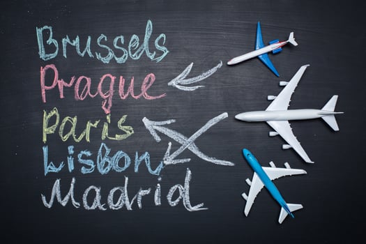 Traveling concept. Toy plane over chalkboard with cities written on it photo