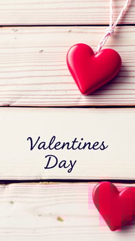 hanging heart on a white wood board with valentine's day written below photo