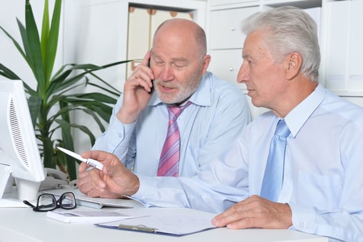 Two old business men sitting at desk and working photo