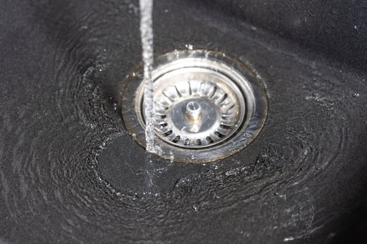 The water falling down from faucet to stainless sink and flow down to water hole, drink concept photo