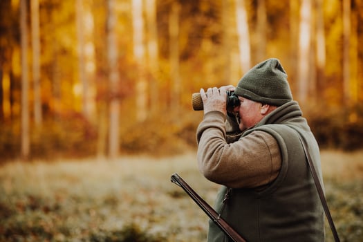 Hunter or ranger with telescope looking out for wild animals in the forest, hunting period, autumn season, hunting and people concept photo