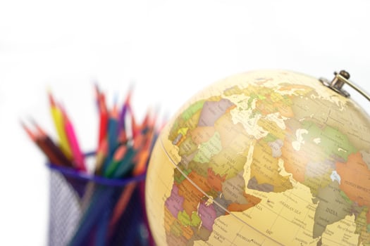 Focus globe and blur crayon or colored pencils behind in box on white background. Learning, study and education concept. photo
