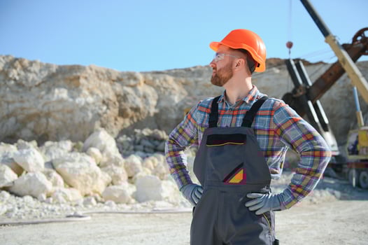 Worker in hardhat standing in stone quarry photo