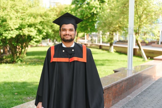 Handsome indian graduate in graduation glow with diploma photo