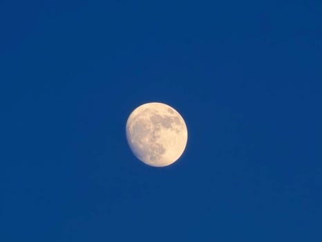 The moon is seen in a clear blue sky photo