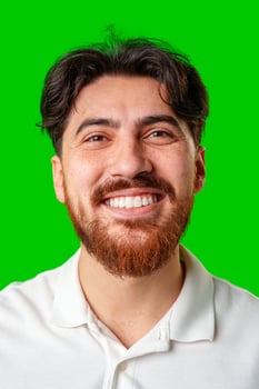 A smiling young man with a beard poses against a bright green background photo
