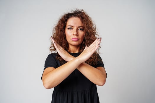 Woman in a black dress standing against a gray background with arms crossed photo