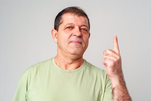 A man in a light green shirt raises his finger, signifying an important message photo