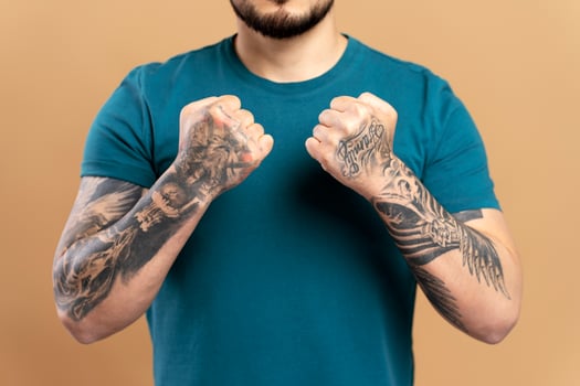 Tattooed man clenching fists on beige background photo