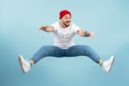Young man jumping spreading legs and arms on blue background photo
