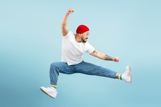 Young man jumping doing splits in mid air on blue background photo