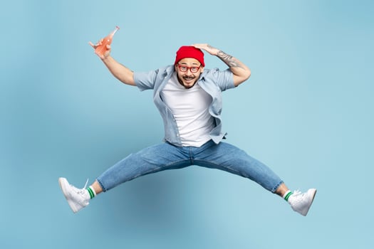Excited man jumping with bottle of drink on blue background photo