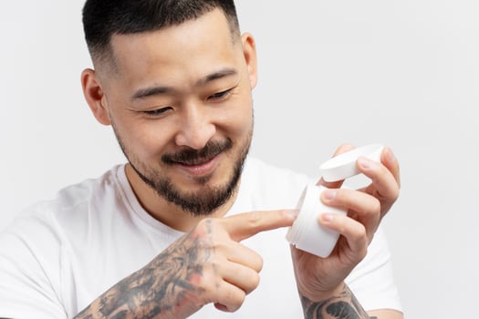 Handsome young man applying moisturizing cream on finger photo