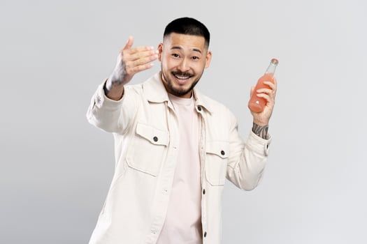 Young man holding pink drink inviting to join party photo