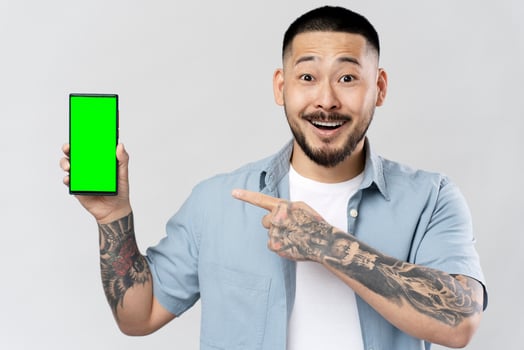 Excited man showing smartphone with green screen photo