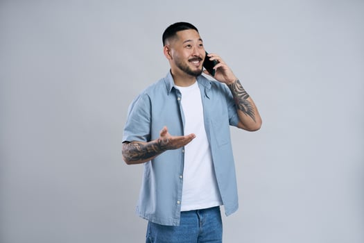 Young asian man with tattoos is talking on the phone and gesturing with hand photo