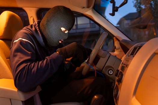 Masked thief hotwiring car ignition system in vehicle theft attempt photo